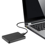 Disque dur externe noir connecté à un ordinateur portable via un câble USB, idéal pour le stockage de données et la sauvegarde de fichiers.