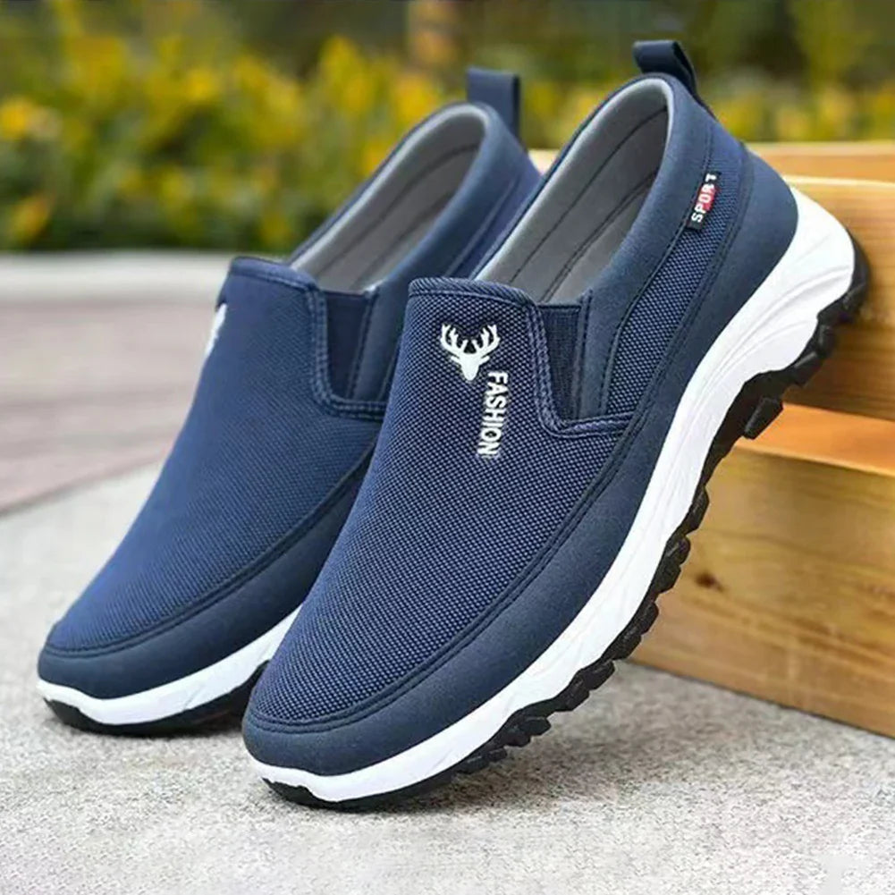 Chaussures de sport bleues pour hommes, style slip-on, semelle blanche antidérapante, logo cerf, idéales pour marche et activités extérieures.