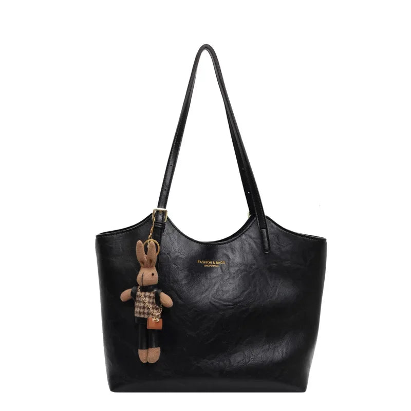 Sac à main noir en cuir avec porte-clés peluche lapin, design élégant et moderne, accessoire mode femme, idéal pour toutes occasions.