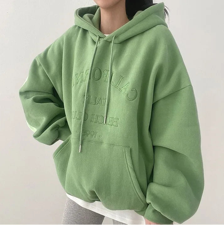 Sweat à capuche vert oversize avec inscription, mode décontractée, tendance automne, femme, style confortable, manches longues, poche kangourou.