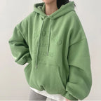 Sweat à capuche vert oversize avec inscription, mode décontractée, tendance automne, femme, style confortable, manches longues, poche kangourou.