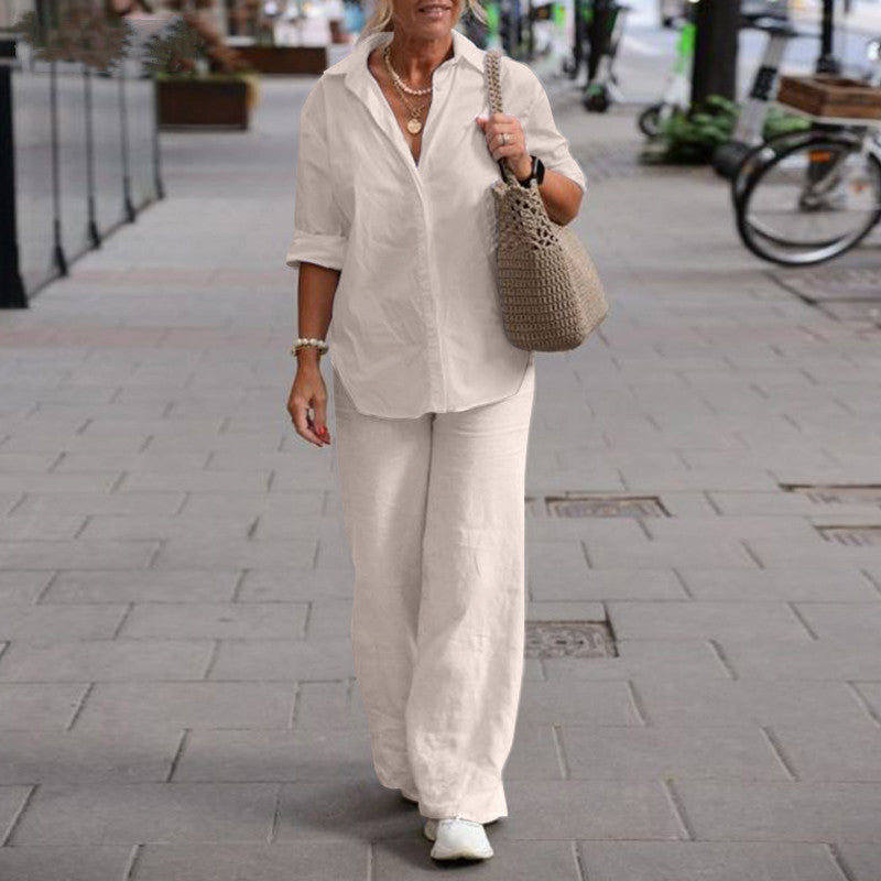 Femme en tenue décontractée blanche, chemise et pantalon ample, marchant en ville avec un sac en crochet beige. Mode urbaine élégante et confortable.