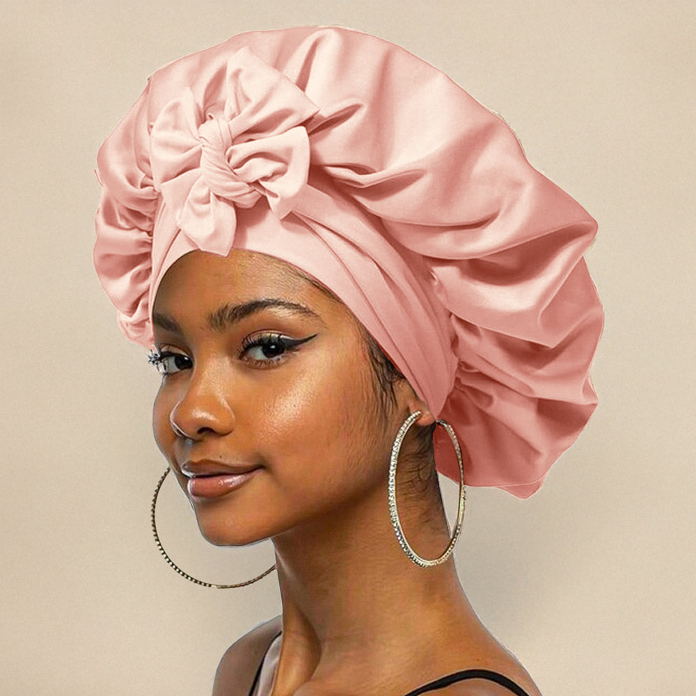 Jeune femme portant un bonnet en satin rose avec un nœud, boucles d'oreilles créoles, fond beige. Mode, accessoires cheveux, élégance.