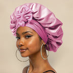 Femme portant un bonnet en satin rose avec un nœud, boucles d'oreilles créoles, fond beige. Mode, accessoires cheveux, style élégant.