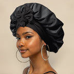 Femme portant un bonnet en satin noir avec un nœud, boucles d'oreilles créoles dorées, maquillage subtil. Mode, accessoires cheveux, élégance.