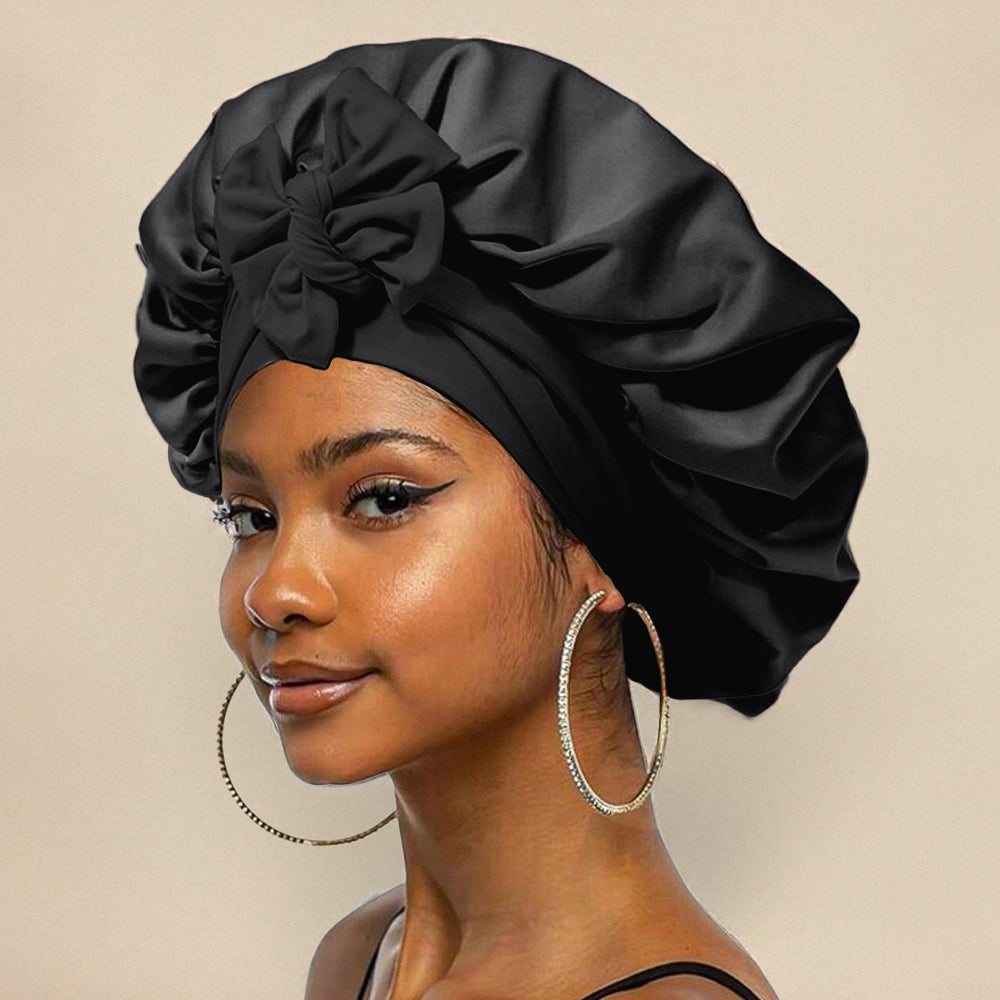 Femme portant un bonnet en satin noir avec un nœud, boucles d'oreilles créoles dorées, maquillage subtil. Mode, accessoires cheveux, élégance.
