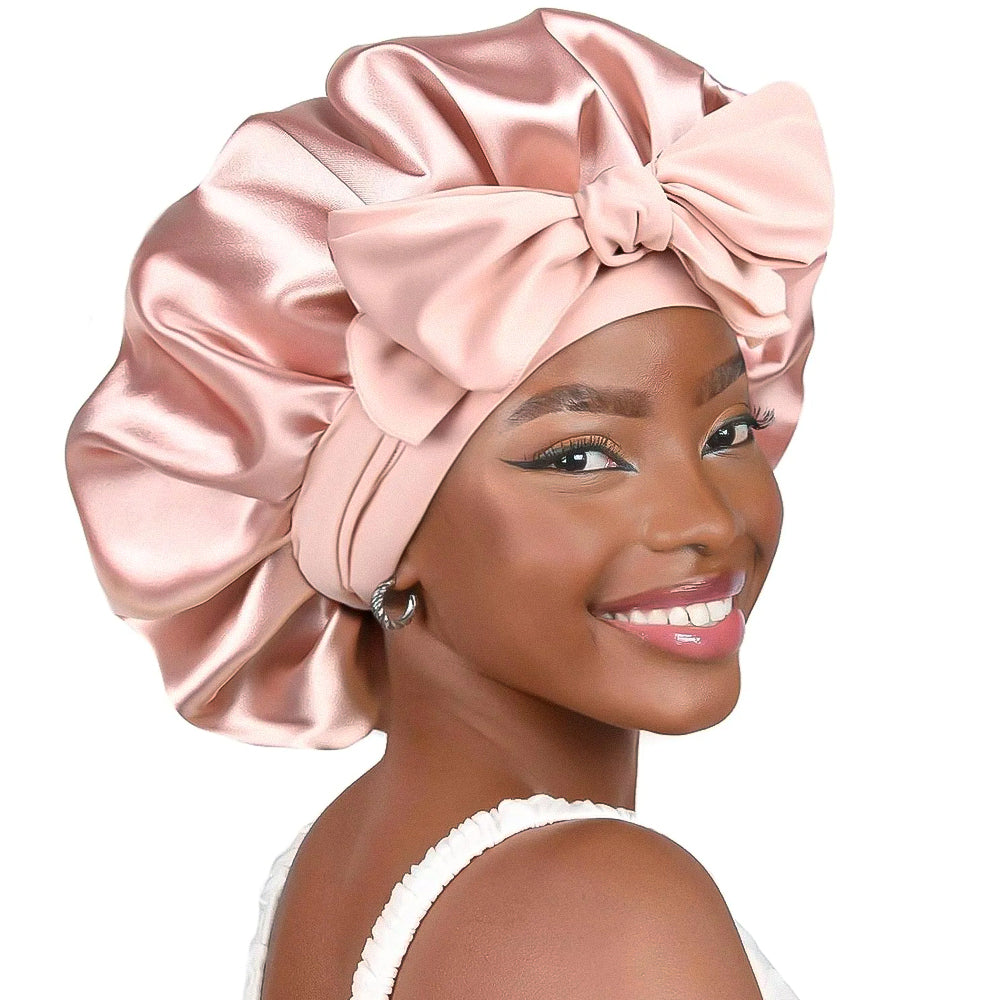 Femme souriante portant un bonnet en satin rose avec un nœud, maquillage élégant, boucle d'oreille argentée. Accessoire cheveux mode, soin capillaire.