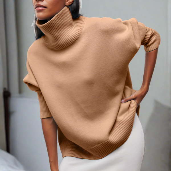 Femme portant un pull col roulé beige, manches retroussées, style décontracté chic, mode automne-hiver, intérieur moderne.