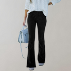 Femme en pull blanc et pantalon noir évasé, tenant un sac à main bleu. Mode automne-hiver, tenue décontractée chic, style moderne.