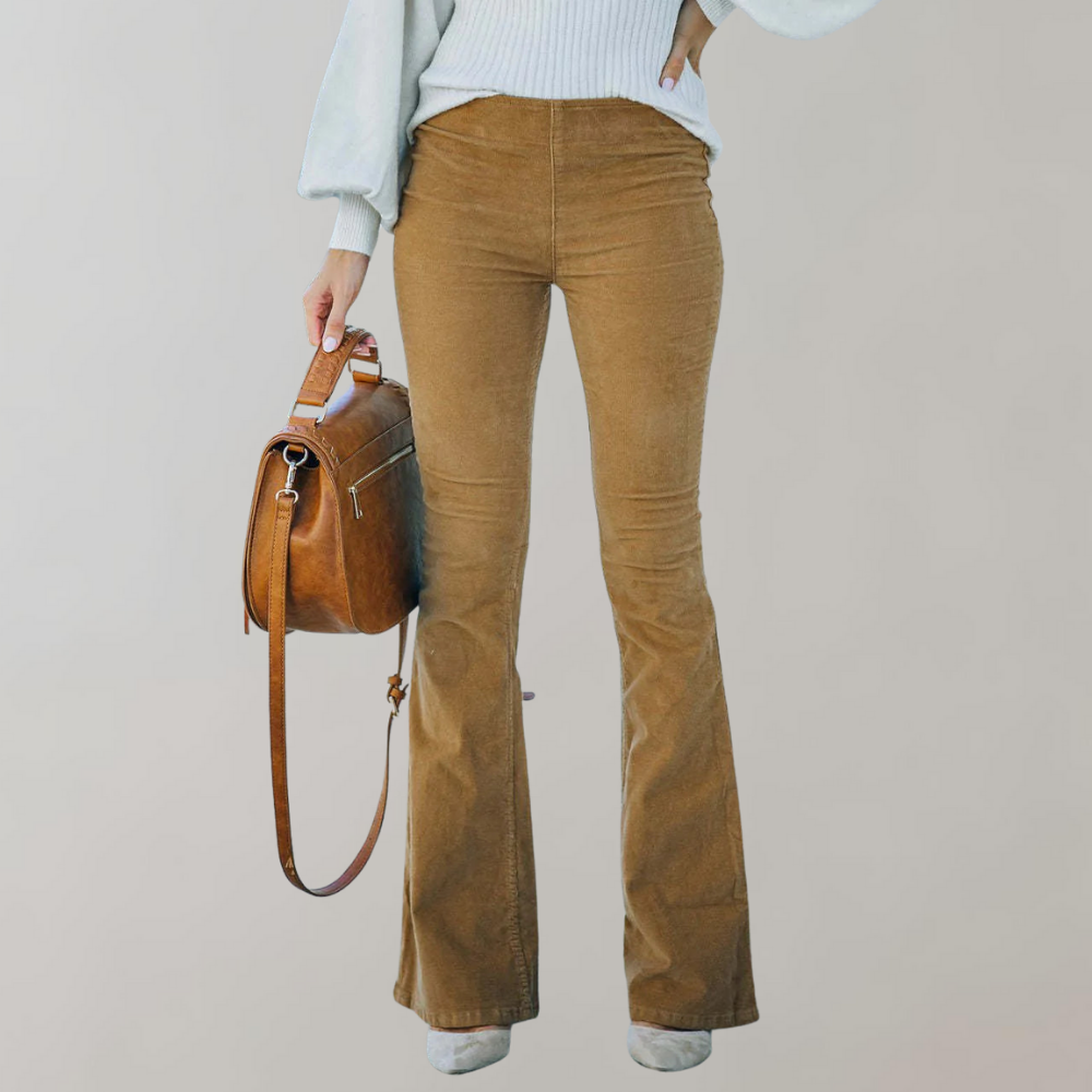 Femme portant un pantalon en velours côtelé marron évasé, pull blanc, tenant un sac à main en cuir marron. Mode automne-hiver, style décontracté.