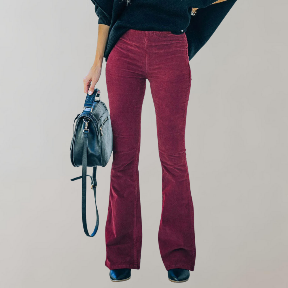 Femme en pantalon évasé bordeaux, pull noir, tenant un sac à main en cuir noir. Mode automne, style chic et décontracté.