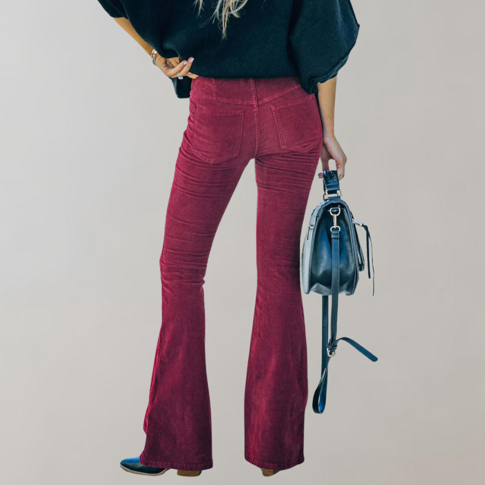 Femme en pantalon patte d'éléphant rouge, portant un sac à main noir. Mode rétro, style années 70, tendance automne-hiver.