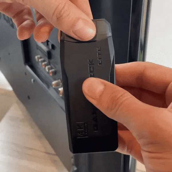 Main tenant une clé HDMI noire, connectée à un téléviseur. Adaptateur 4K, streaming, technologie moderne, installation facile.