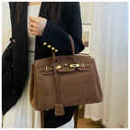Femme tenant un sac à main en cuir marron élégant, style Birkin, avec une tenue chic. Mode féminine, accessoire de luxe, tendance automne.