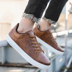 Chaussures en cuir marron pour homme, style décontracté, semelle blanche, portées avec un jean noir retroussé. Mode masculine tendance.