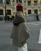Femme en manteau gris devant le théâtre Callao à Madrid, Espagne, avec décorations lumineuses et passants. Scène urbaine animée en hiver.
