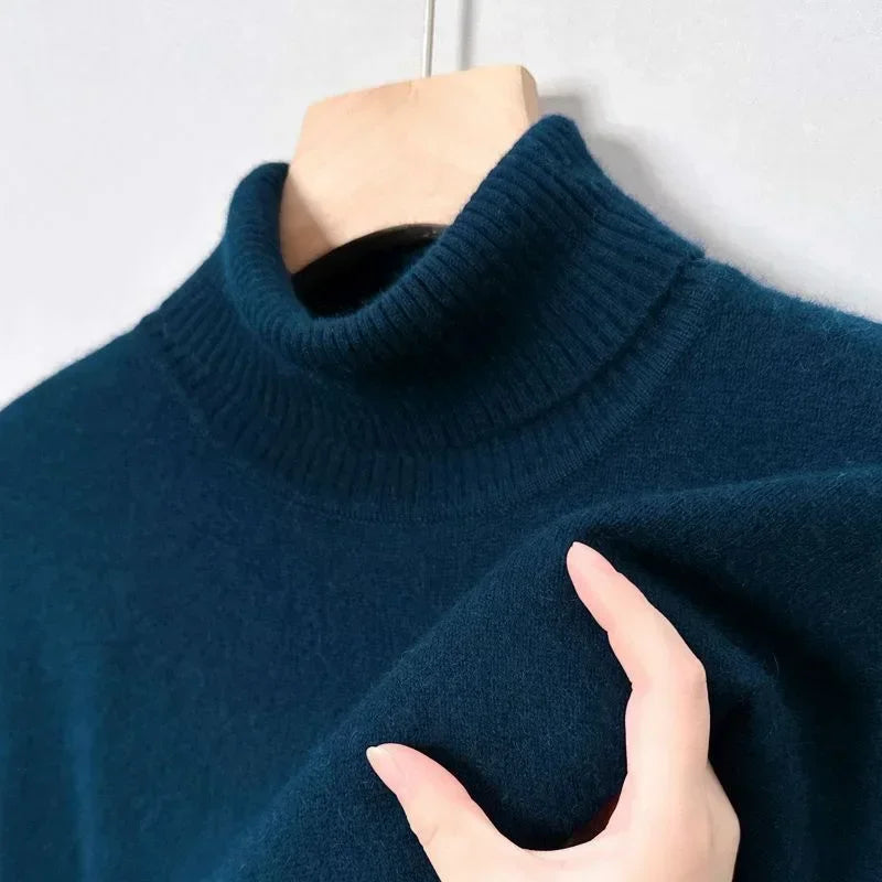 Pull-over en cachemire bleu marine avec col roulé, suspendu sur un cintre en bois. Tissu doux et luxueux, idéal pour l'hiver.