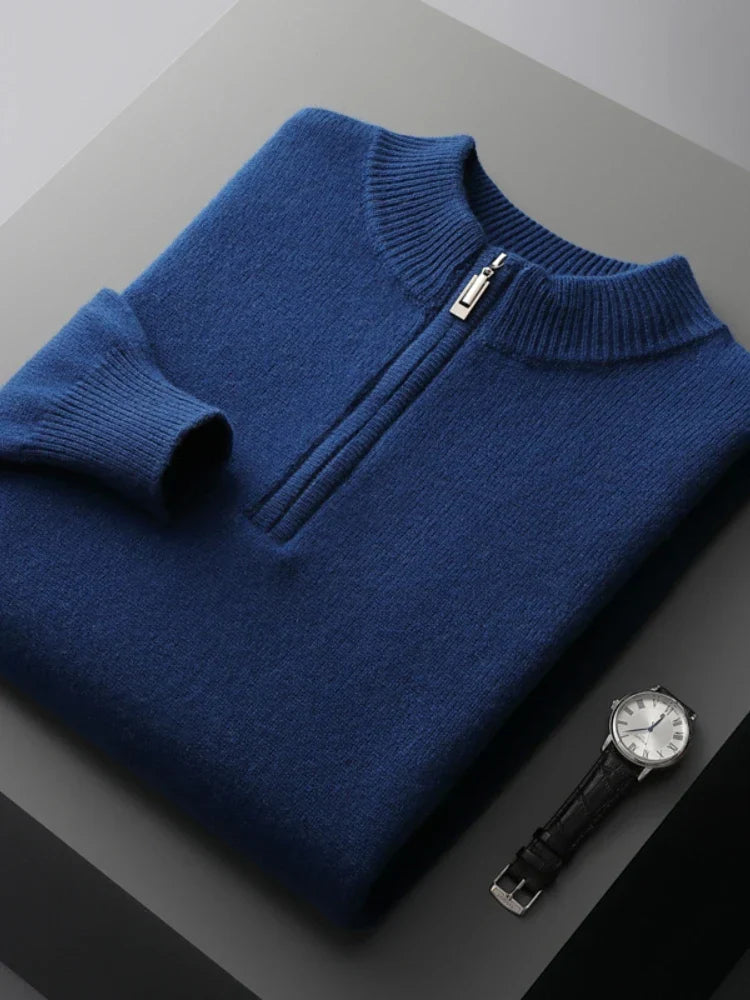 Pull bleu en laine avec fermeture éclair, posé sur une surface grise, accompagné d'une montre-bracelet noire élégante. Mode masculine chic.