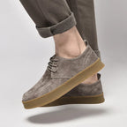 Chaussures en daim gris pour homme, semelle en caoutchouc marron, style décontracté, pantalon retroussé, mode masculine élégante.