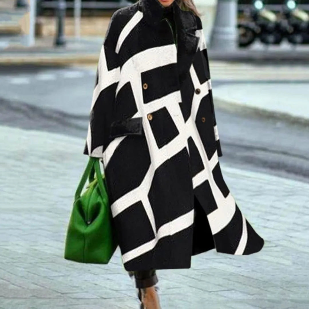 Manteau noir et blanc à motifs géométriques porté par une femme, accompagné d'un sac à main vert vif, sur un trottoir urbain.