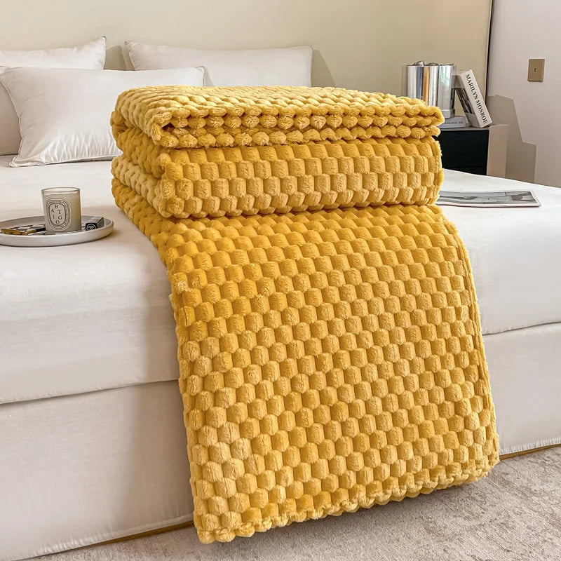 Couverture en peluche jaune texturée sur un lit blanc, avec oreillers blancs et une tasse à café sur la table de chevet. Décoration chambre moderne.