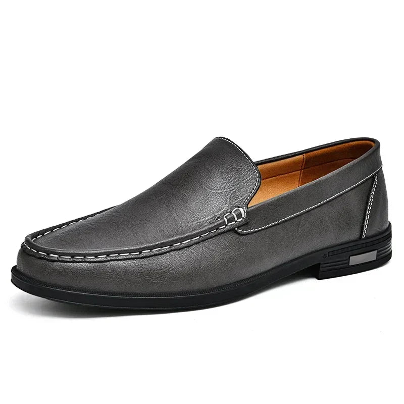 Mocassin en cuir gris pour homme, élégant et confortable, avec coutures blanches contrastantes et semelle noire antidérapante.