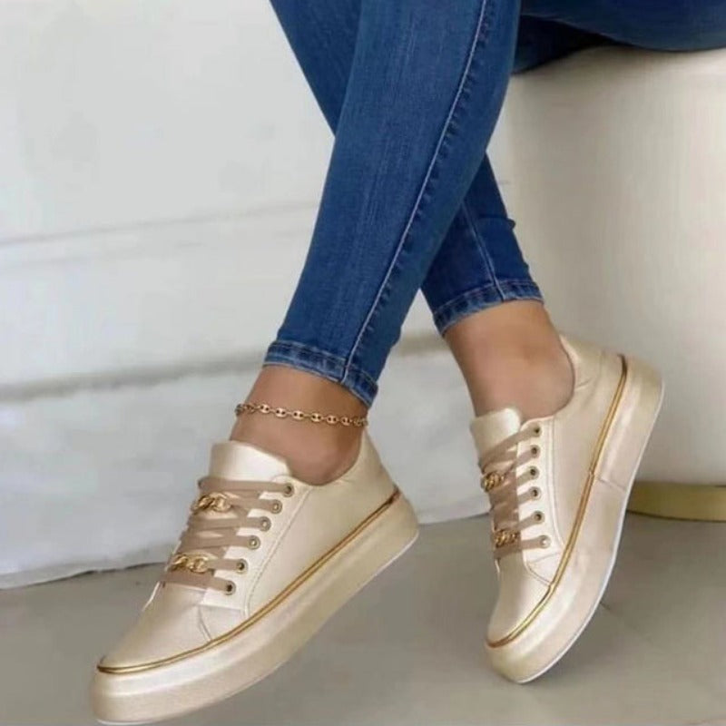 Chaussures dorées élégantes portées avec un jean bleu, posées sur un sol clair. Sneakers tendance pour femme, mode décontractée chic.