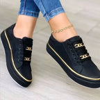 Chaussures noires élégantes avec détails dorés, portées avec un jean bleu. Sneakers tendance pour femme, style moderne et chic.