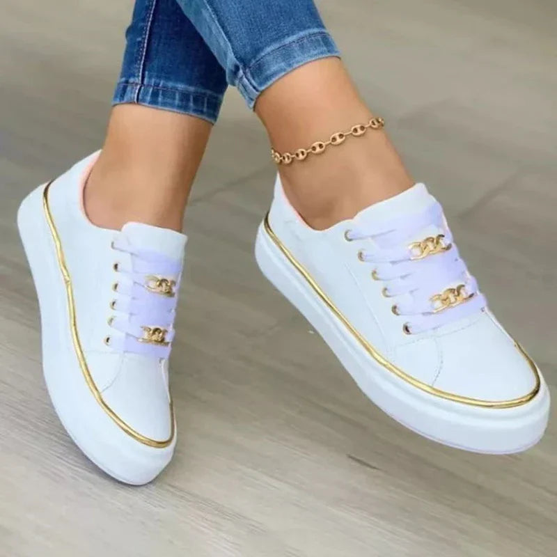 Chaussures blanches décontractées avec détails dorés, portées avec un jean bleu. Sneakers tendance pour femme, style moderne et élégant.