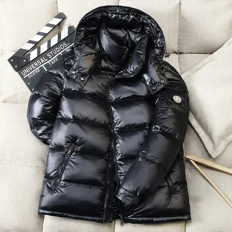 Doudoune noire en duvet brillant posée sur un canapé beige, avec une clapperboard de cinéma. Mode hiver, veste chaude, style urbain.