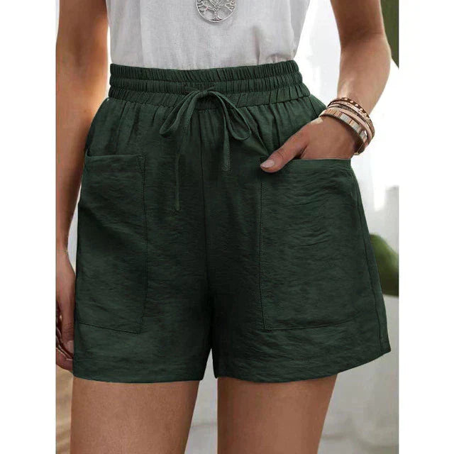 Short vert foncé avec poches avant, taille élastique et cordon de serrage, porté avec un haut blanc. Mode estivale décontractée pour femmes.