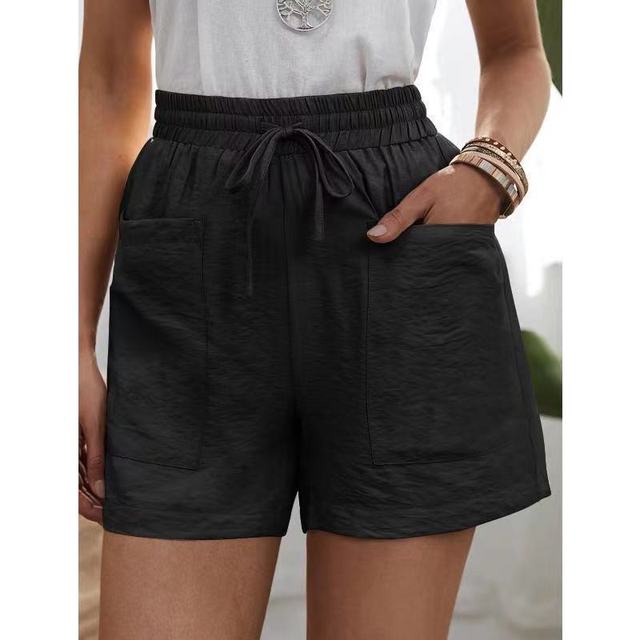 Short noir femme avec poches avant, taille élastique et cordon de serrage, porté avec un t-shirt blanc. Mode estivale décontractée.