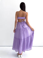 Robe longue violette dos nu, femme de dos, bretelles fines, tissu léger, style estival, élégance décontractée, mode féminine tendance.