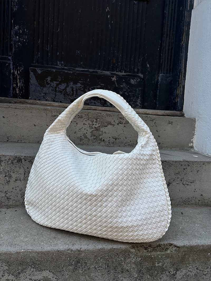 Sac à main blanc tissé en cuir, posé sur des marches en béton. Accessoire mode élégant, tendance, idéal pour un look chic et moderne.