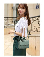 Jeune femme souriante portant un sac à main vert élégant, vêtue d'un haut blanc et d'une jupe verte, posant devant un bâtiment urbain.