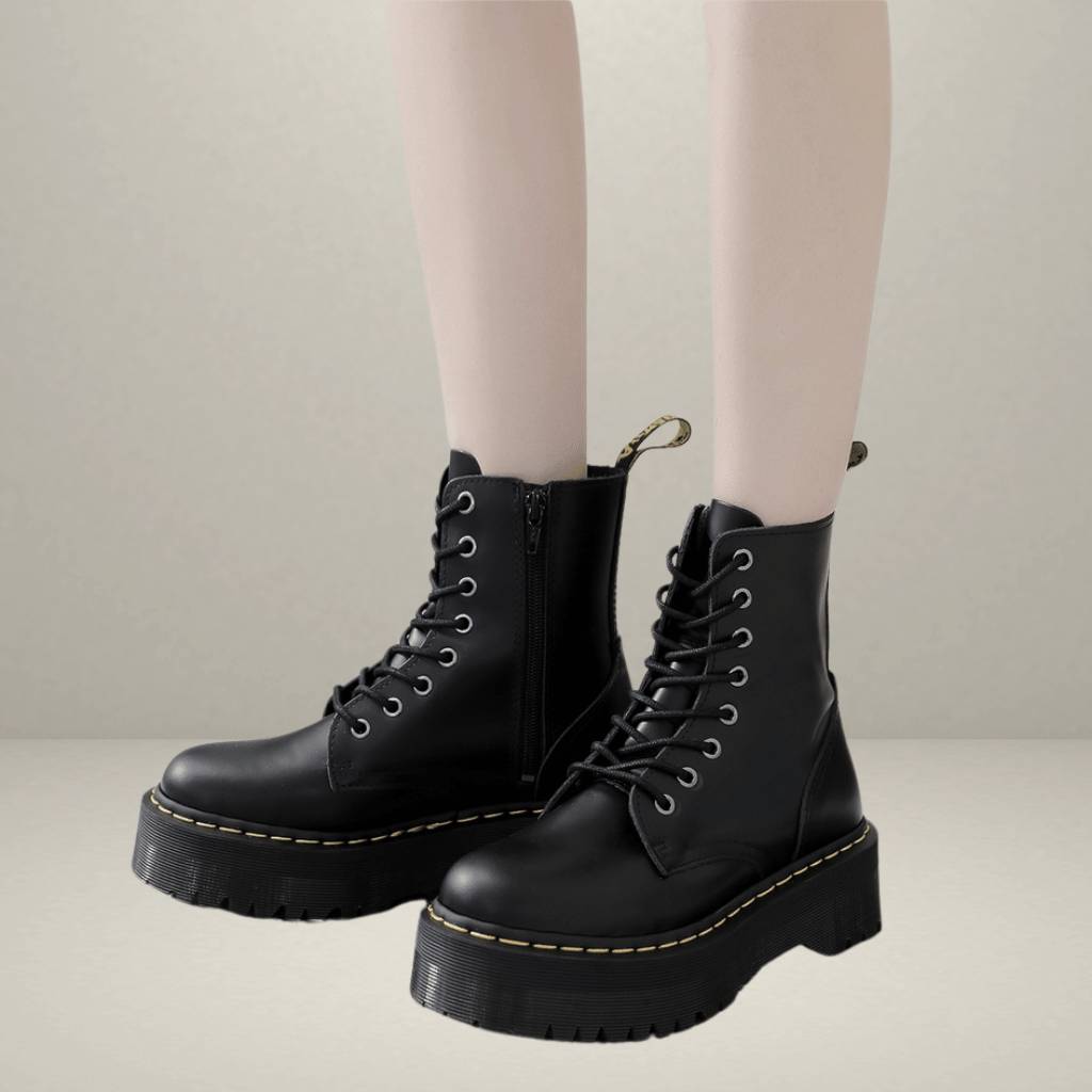Bottes noires à plateforme en cuir avec lacets, portées par une personne. Chaussures tendance, style punk, semelle épaisse, mode automne-hiver.