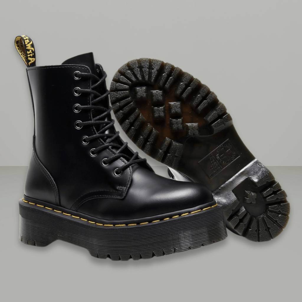 Bottes noires en cuir à lacets avec semelle épaisse et crantée, style combat, sur fond gris. Mode, chaussures robustes, tendance automne-hiver.