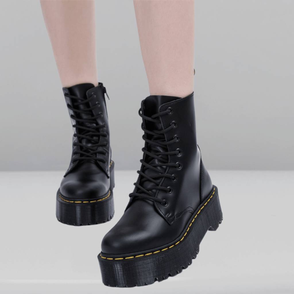 Bottes noires à plateforme épaisse, lacets noirs, sur fond gris. Chaussures tendance, style punk, mode urbaine, semelle crantée.