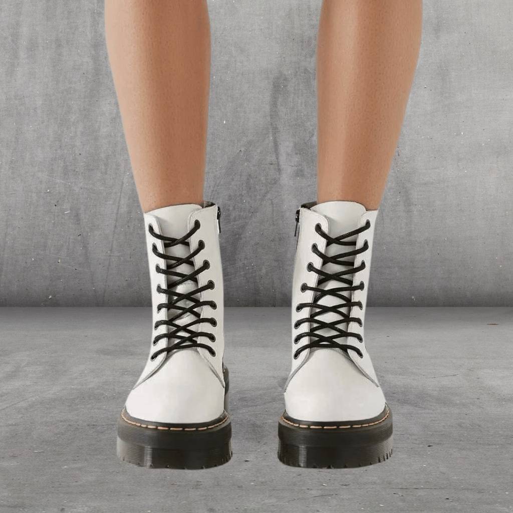 Bottes blanches en cuir avec lacets noirs, style combat, sur fond gris. Chaussures tendance pour femmes, mode automne-hiver, look urbain.