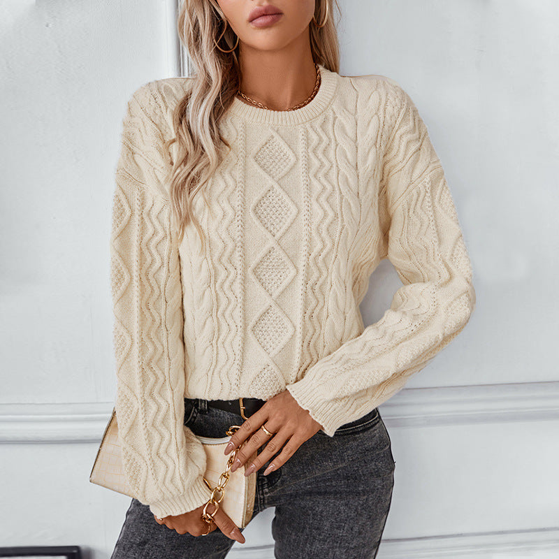Femme portant un pull en tricot torsadé beige, manches longues, avec un sac à main beige. Mode automne-hiver, style décontracté et élégant.