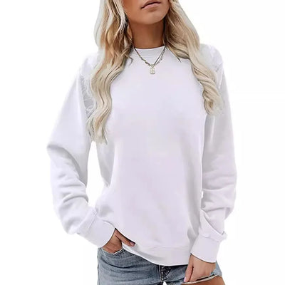 Femme portant un pull blanc à manches longues, col rond, avec un collier doré, posant en jean. Mode décontractée, style tendance.