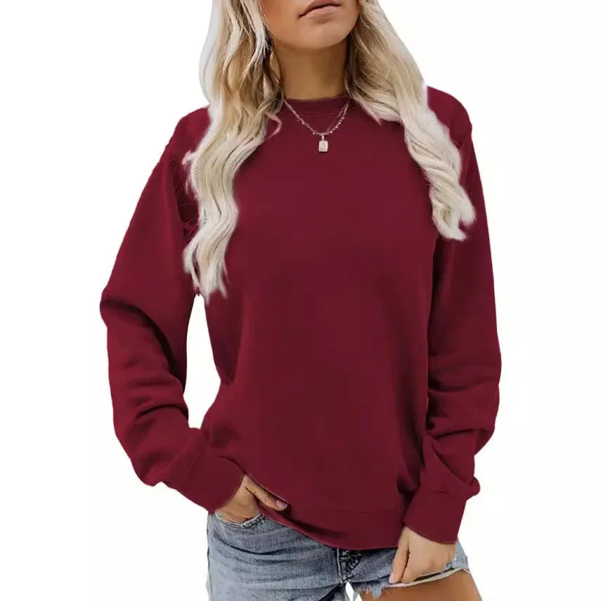 Femme portant un pull bordeaux à manches longues, col rond, avec un collier, et un short en jean. Mode décontractée, tendance automne-hiver.