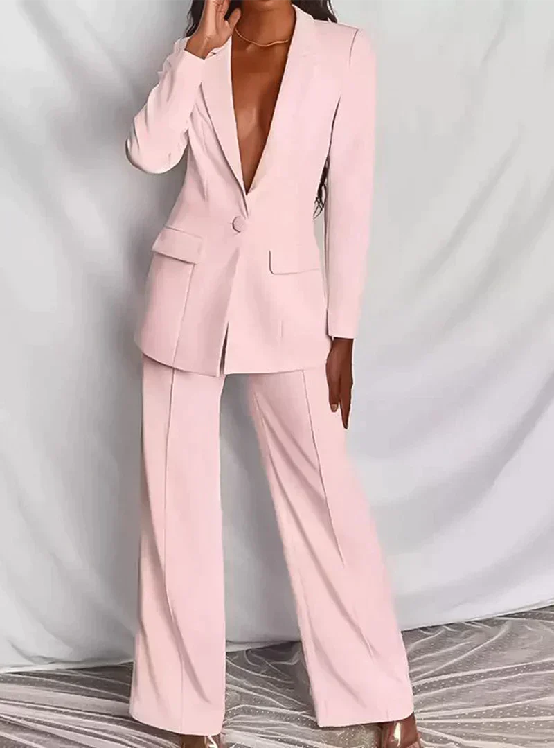 Femme portant un tailleur pantalon rose pâle élégant, veste à un bouton, sur fond neutre. Mode féminine chic, tenue professionnelle moderne.