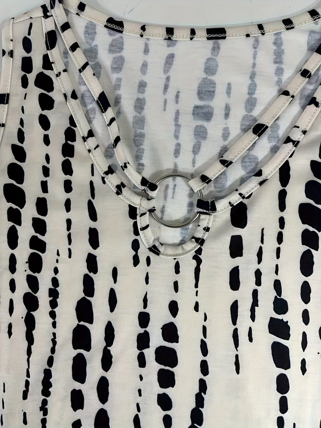 Débardeur blanc à motifs noirs abstraits, col rond avec anneau décoratif. Mode féminine, tendance, vêtement d'été élégant et moderne.