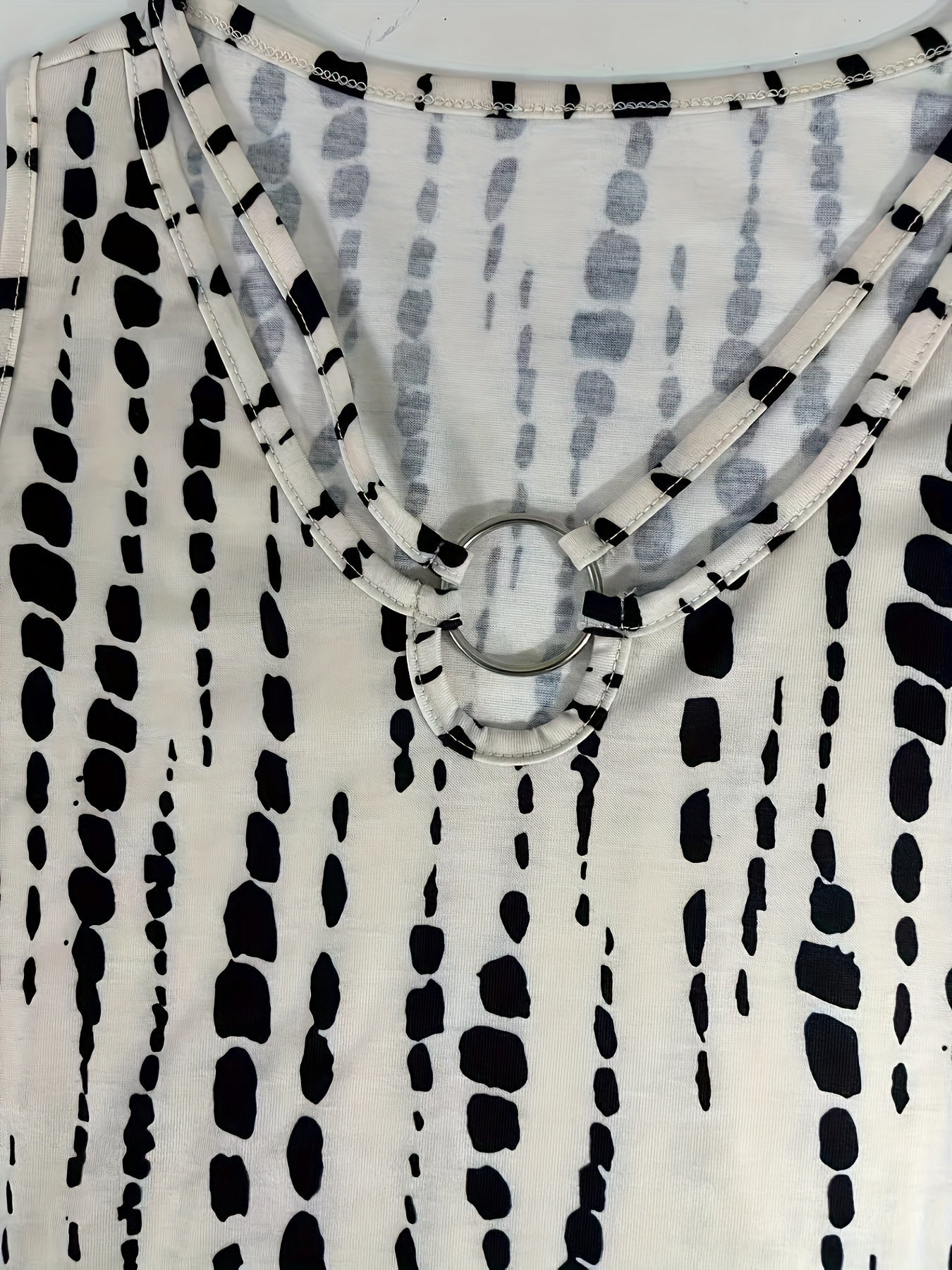Débardeur blanc à motifs noirs abstraits, col rond avec anneau décoratif. Mode féminine, tendance, vêtement d'été élégant et moderne.