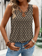 Femme portant un débardeur à motif géométrique noir et beige avec anneau décoratif, associée à un jean bleu. Mode estivale chic et tendance.