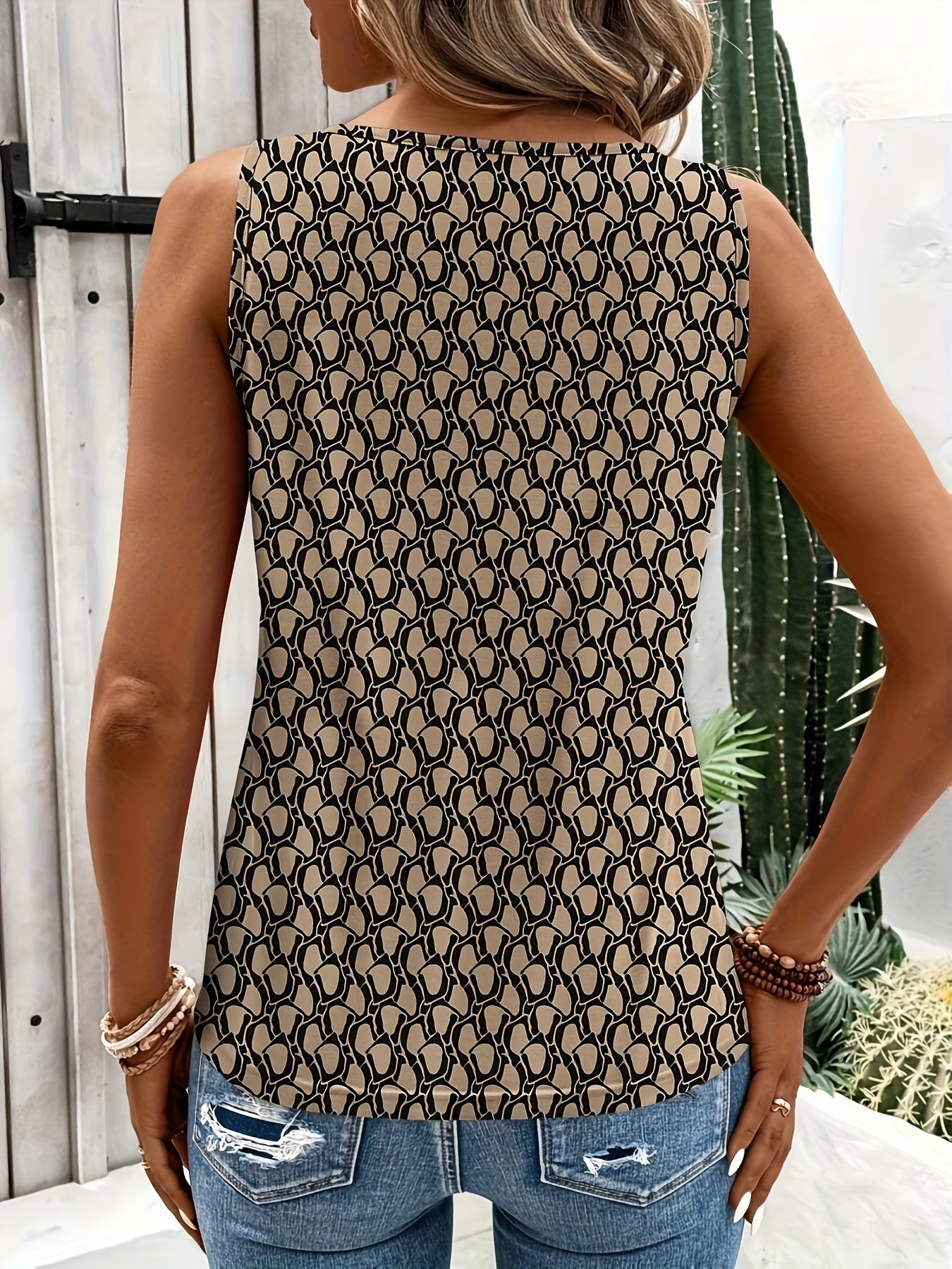 Femme portant un débardeur à motifs géométriques noirs et beiges, associée à un jean déchiré. Style décontracté, mode féminine tendance.