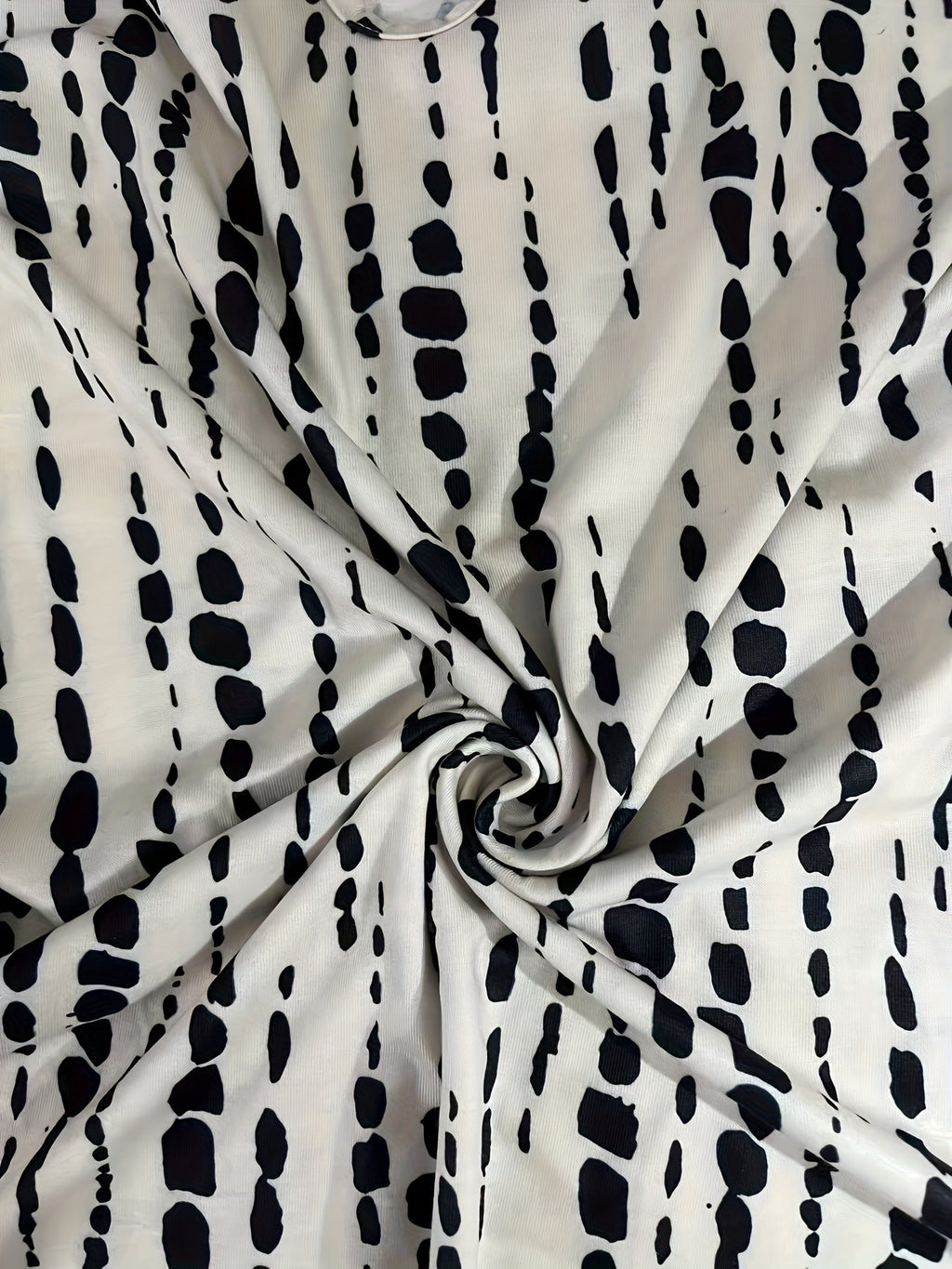 Tissu blanc à motifs noirs abstraits, style moderne. Design textile élégant, idéal pour la mode et la décoration intérieure tendance.