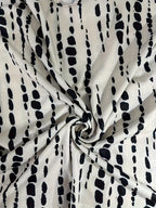 Tissu blanc à motifs noirs abstraits, style moderne. Design textile élégant, idéal pour la mode et la décoration intérieure tendance.