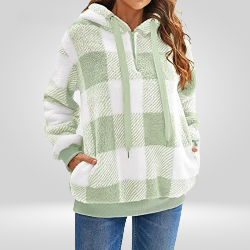 Femme portant un sweat à capuche à carreaux vert et blanc, manches longues, poches avant, style décontracté, mode automne-hiver.